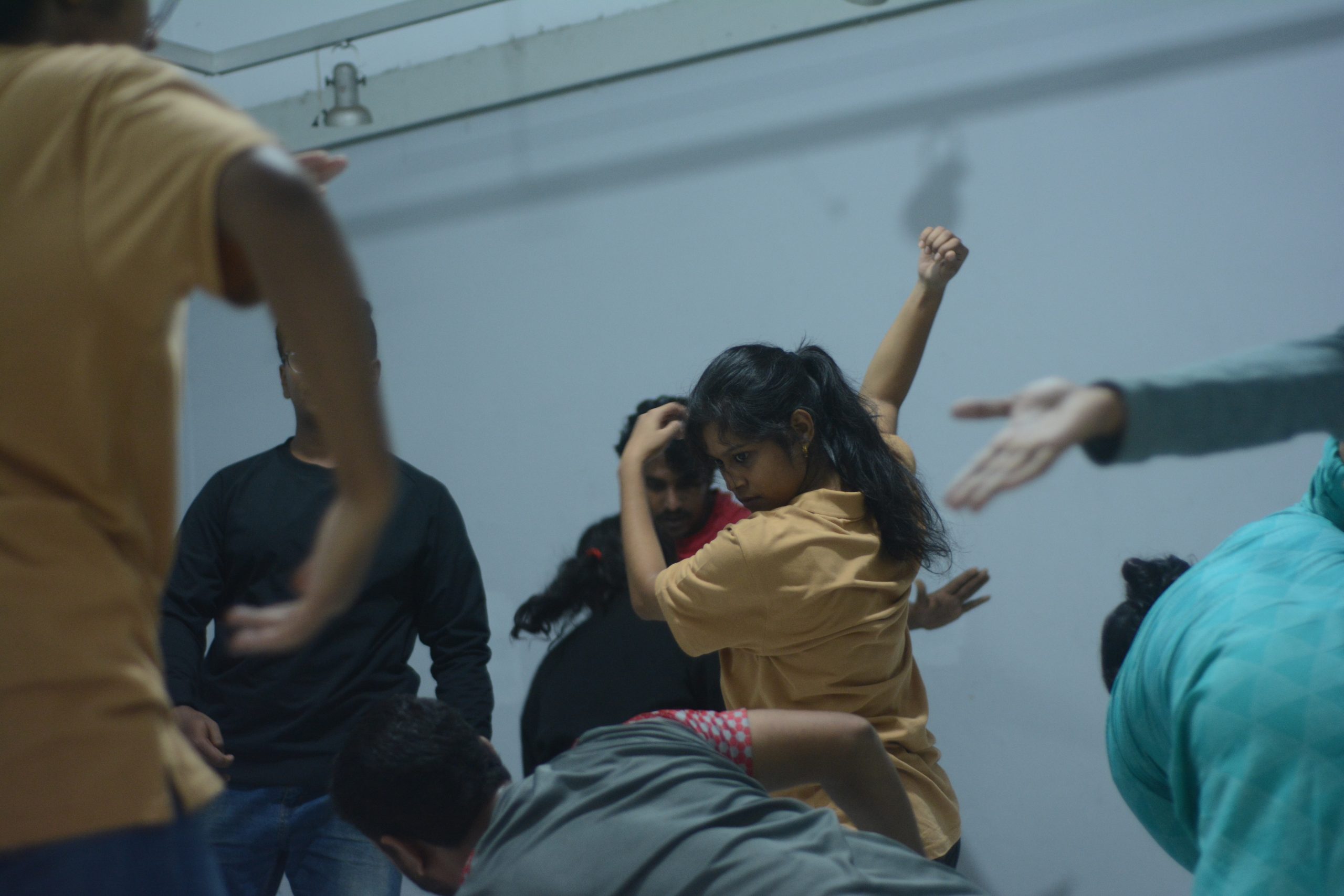 Varias personas de un taller de danza moviéndose libremente, unos levantan los brazos, otros se agachan y otros de pie