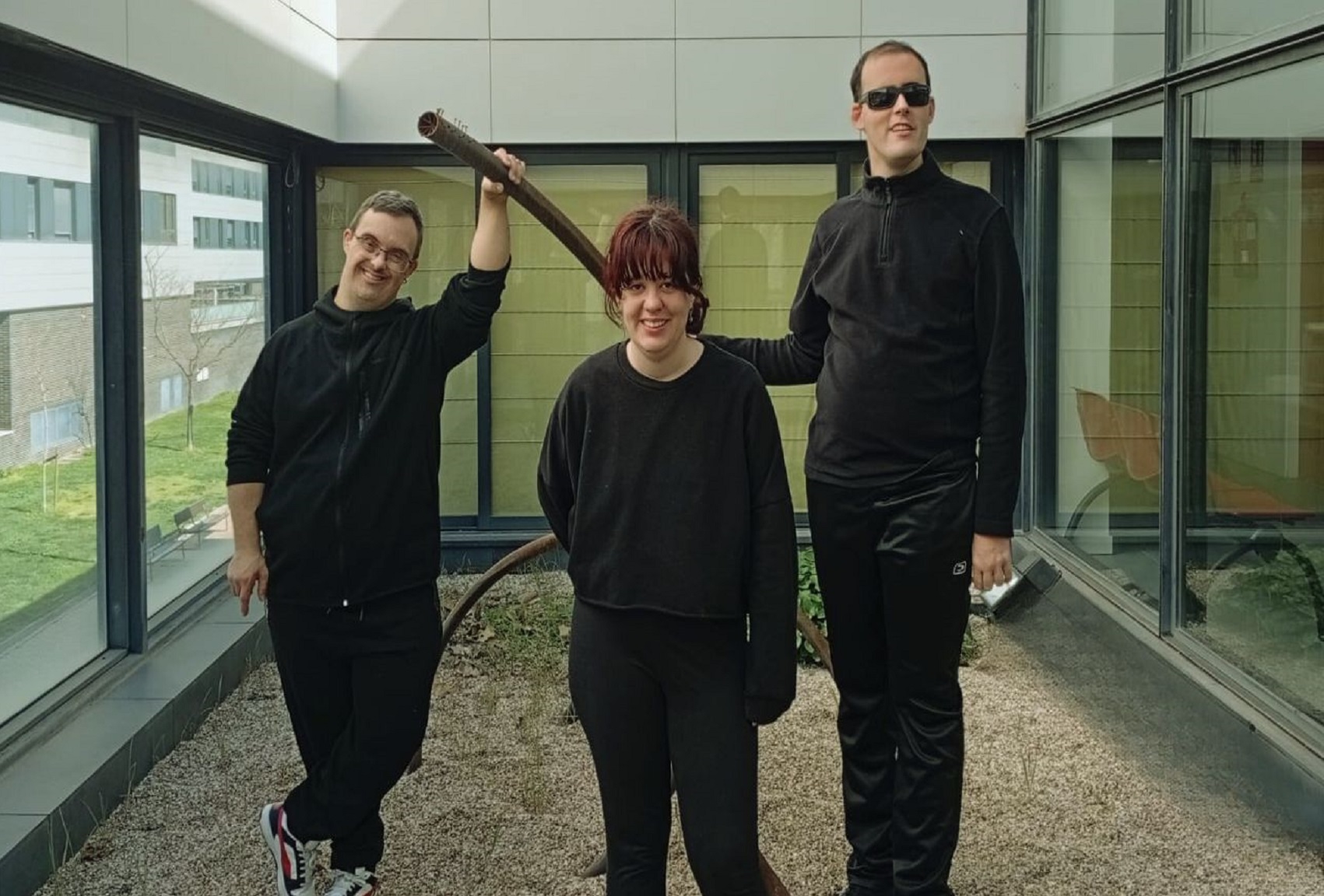 Foto del espectáculo. Tres personas vestidas de negro posan en un patio.