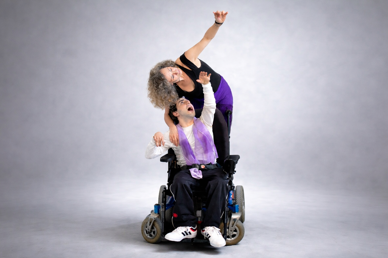 Imagen de escena. Dos personas, una en silla de ruedas, señalan hacia el cielo.