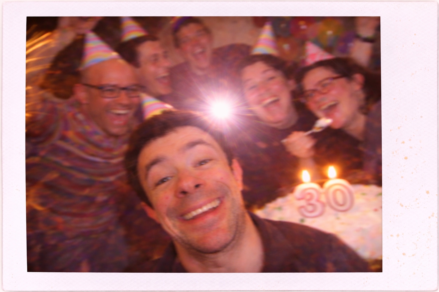 Imagen del espectáculo. Un grupo de personas celebra un cumpleaños, todos van con gorros de cumpleaños. En primer plano el cumpleañero y al fondo se ve una tarta con velas con el número 30