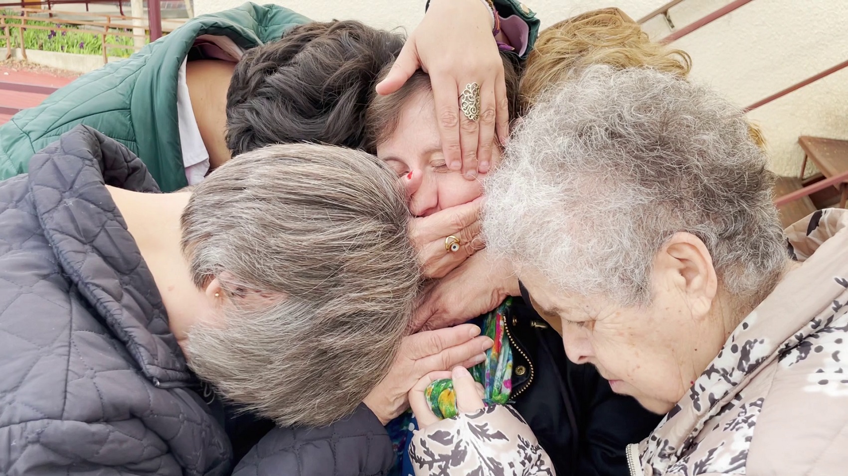 Imagen del espectáculo. Cuatro mujeres con las cabezas agachadas rodean a otra y le tapan con sus manos la boca y ojos.