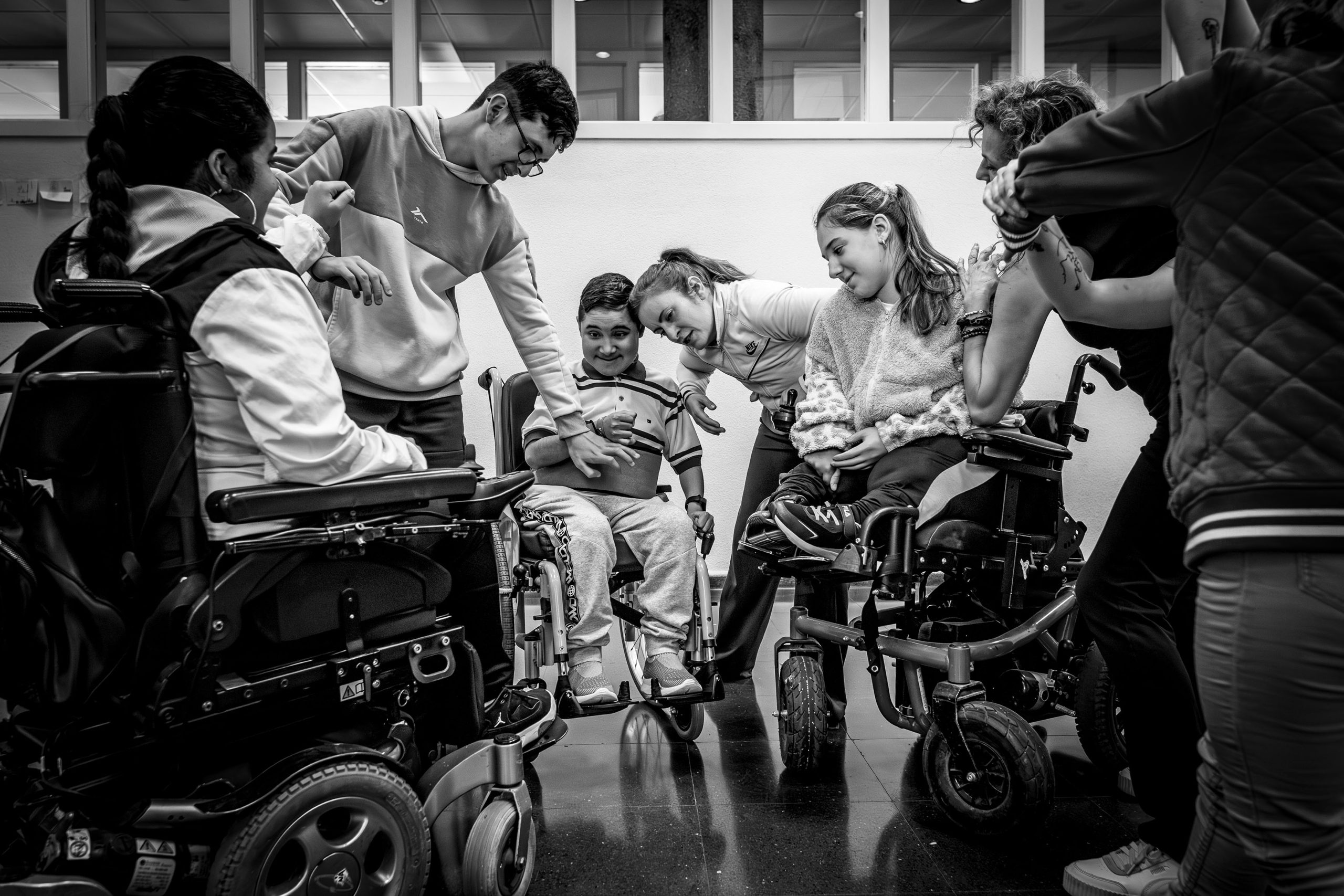 Fotografía de la exposición. Foto en blanco y negro con un grupo de personas reunidas, unas de pie y otras en sillas de ruedas.